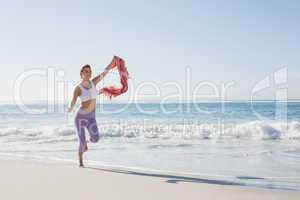 Sporty blonde jogging on the beach with a scarf