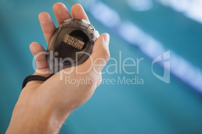 Swimming coach looking at his stopwatch by the pool