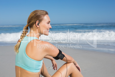 Fit woman sitting on the beach taking a break smiling