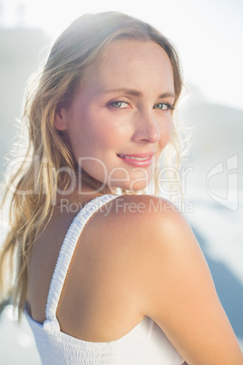 Pretty blonde standing at the beach in white sundress