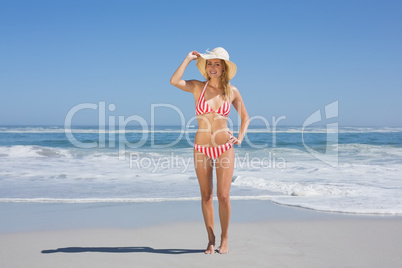 Gorgeous fit woman in striped bikini and sunhat at beach