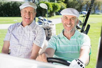 Golfing friends driving in their golf buggy smiling at camera