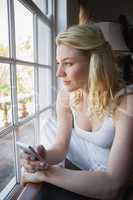 Pretty blonde sitting by the window sending a text