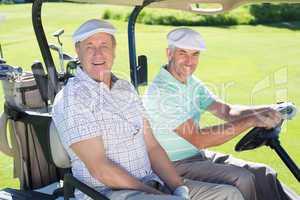 Golfing friends driving in their golf buggy smiling at camera