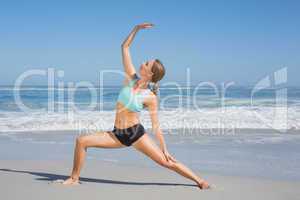 Fit woman standing on the beach in warrior pose