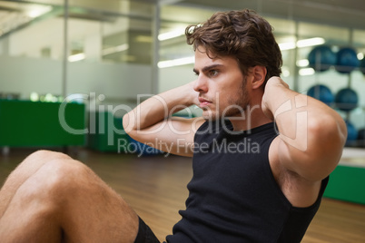 Fit handsome man doing sit ups in fitness studio