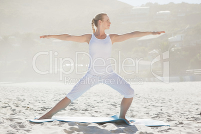 Calm woman standing in warrior pose on beach