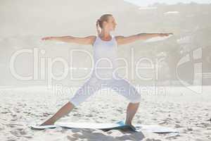 Calm woman standing in warrior pose on beach