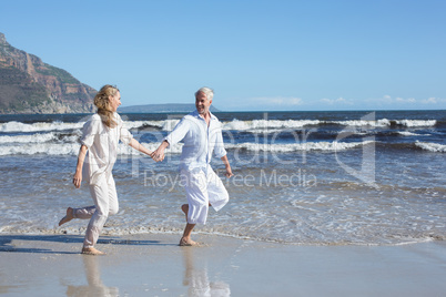 Happy couple skipping barefoot on the beach