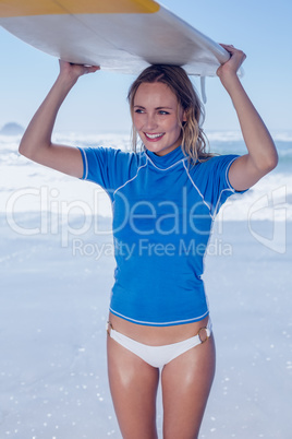 Blonde happy surfer holding her board on the beach