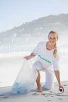 Blonde activist picking up trash on the beach