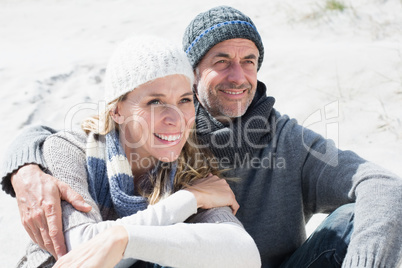 Attractive couple smiling on the beach in warm clothing