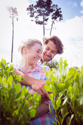 Smiling couple embracing outside among the bushes