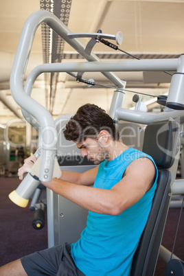 Focused man using weights machine for arms