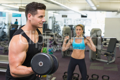 Muscular man and woman lifting weights