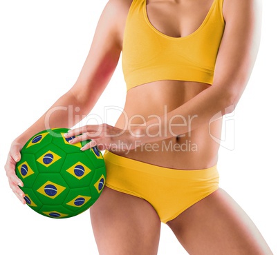Fit girl in yellow bikini holding brazil football