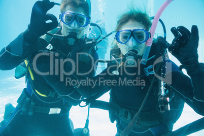 Friends on scuba training submerged in swimming pool looking to