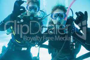 Friends on scuba training submerged in swimming pool looking to