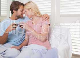 Happy couple sitting on couch with red wine