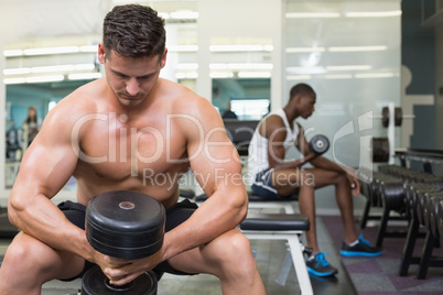 Handsome bodybuilder holding heavy black dumbbell