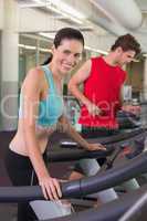 Fit happy couple running together on treadmills