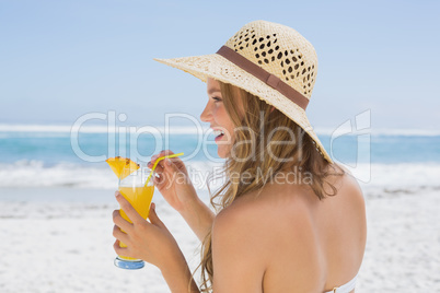 Pretty blonde in bikini holding cocktail on the beach