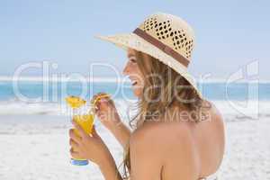 Pretty blonde in bikini holding cocktail on the beach