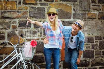 Hip young couple standing by brick wall with their bikes