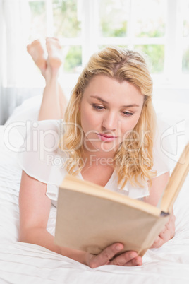 Pretty blonde lying on bed with book