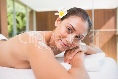 Beautiful smiling brunette lying on massage table with salt scru