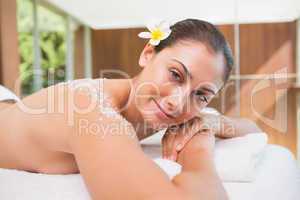 Beautiful smiling brunette lying on massage table with salt scru