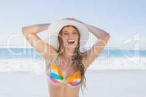 Beautiful girl on the beach smiling in white straw hat and bikin