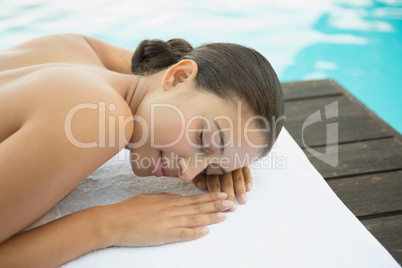 Peaceful brunette lying on towel poolside