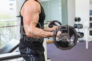 Muscular bodybuilder lifting heavy black barbell weight