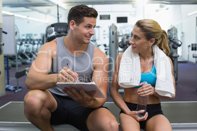 Female bodybuilder sitting with personal trainer talking