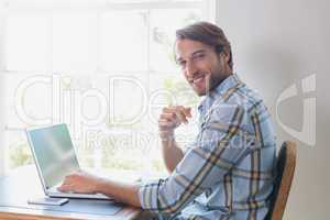 Handsome man sitting at table using laptop