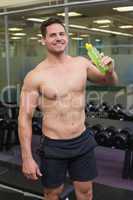 Shirtless bodybuilder drinking sports drink smiling at camera