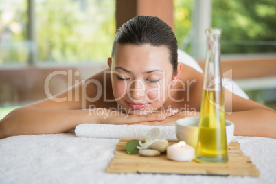 Brunette lying on massage table with tray of beauty treatments