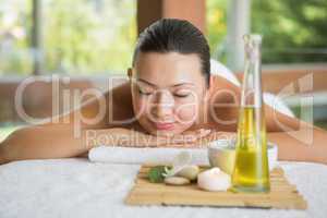 Brunette lying on massage table with tray of beauty treatments