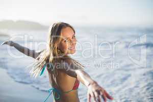 Content blonde standing on the beach in bikini with arms out