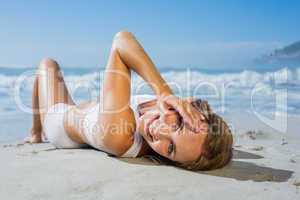 Fit smiling woman lying on the beach