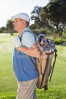 Golfer standing holding his golf bag