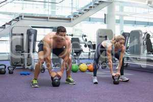 Bodybuilding man and woman lifting kettlebells in a squat