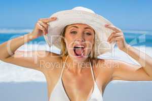 Smiling blonde in white bikini and sunhat on the beach