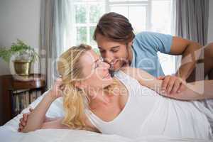 Cute couple relaxing on bed about to kiss