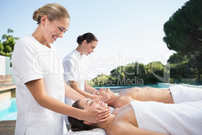 Content couple enjoying head massages poolside