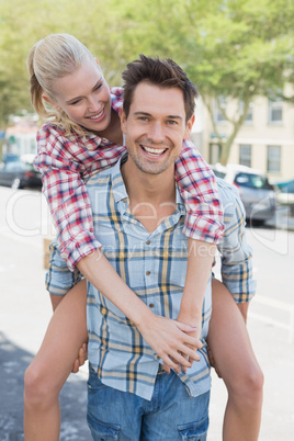 Young hip man giving his blonde girlfriend a piggy back