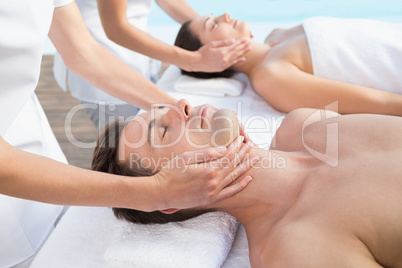 Content couple enjoying head massages poolside