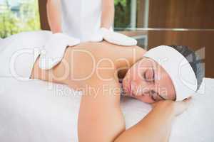 Beauty therapist rubbing womans back with heated mitts