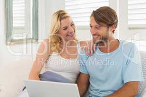 Young couple sitting on the couch together using laptop